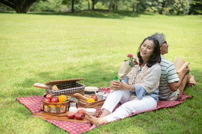 Smiling young woman sitting in basket on grass