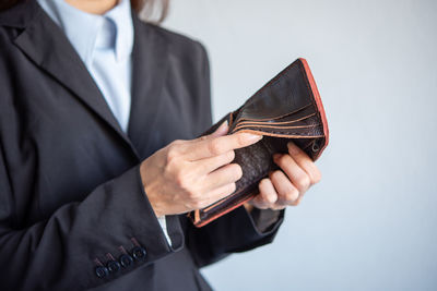 Midsection of businessman holding paper currency against white background