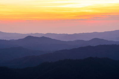 Scenic view of silhouette mountains against orange sky