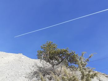 Low angle view of vapor trail against clear blue sky