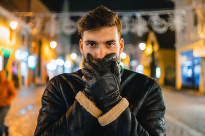 Portrait of young man standing at night during winter