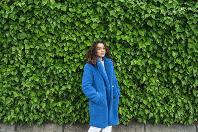 Portrait of smiling young woman standing against plants