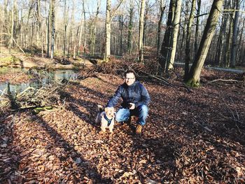 Portrait of father with dog sitting in forest