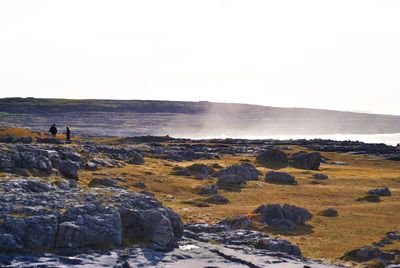 Man standing on rock against sky