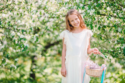 Young woman holding red flower standing in basket