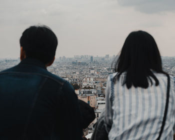 Rear view of woman looking at city buildings against sky