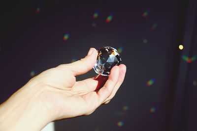 Cropped hand crystal ball against black curtain