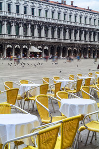 Empty chairs and tables against building at piazza san marco
