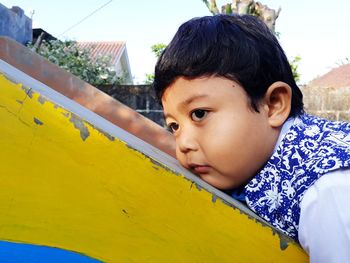 Side view of cute boy looking away while lying outdoors