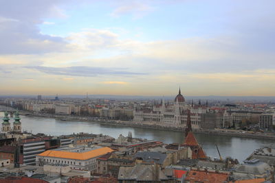 High angle view of buildings by river against sky in city