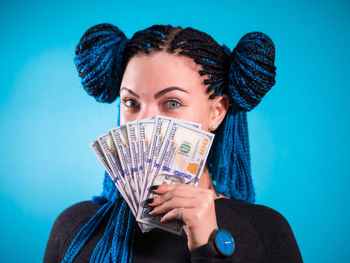 Close-up portrait of young woman against blue background