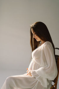 Young woman looking away against wall