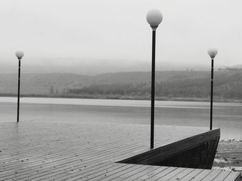 Street light on footpath by lake against sky