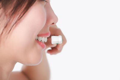 Close-up of woman brushing teeth over white background