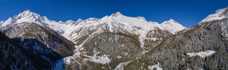 Panoramic view of snowcapped mountains against clear blue sky