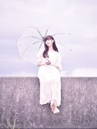 Woman standing with umbrella against sky