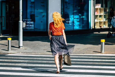 Full length rear view of woman walking on road