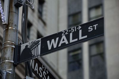 Low angle view of sign on pole against building