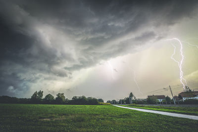 Scenic view of lightning over field against sky