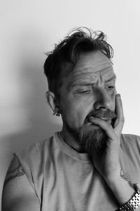 Thoughtful shocked man looking down against wall