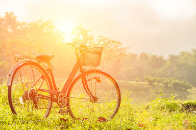 Bicycle parked on field against sky during sunset