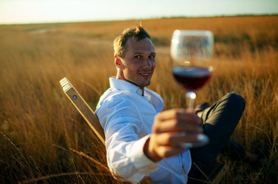 Famer with red wine enjoying in field at sunset