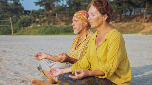 Man and woman meditating while sitting at beach