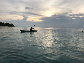 Silhouette man on sea against sky during sunset