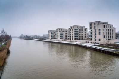 Bridge over river by buildings against sky in city