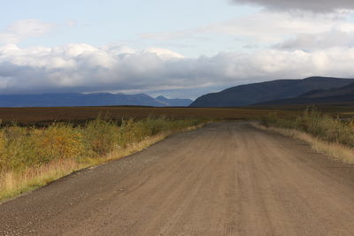 Empty road along landscape and mountains against sky