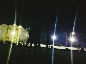 Woman standing on illuminated street light at night