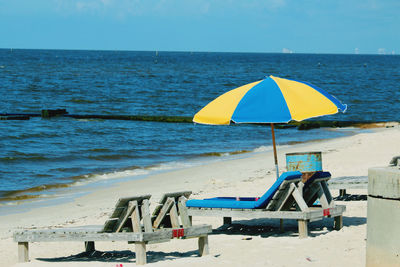 Deck chairs on beach against sky