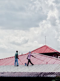 People standing on roof against sky