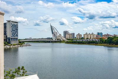 Bridge over river by buildings against sky