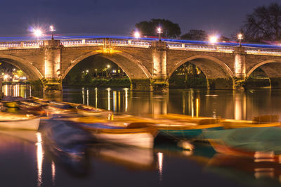 Illuminated bridge over river against sky at night