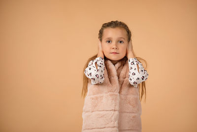 Portrait of cute girl standing against pink background