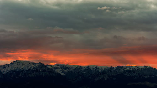 Scenic view of snowcapped mountains against dramatic sky