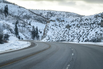 Road amidst snowcapped mountains against sky