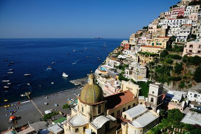 Buildings by sea on cliff against clear sky at positano