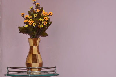 Close-up of flower vase on table against wall