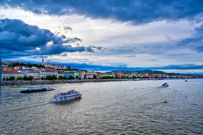 City at waterfront against cloudy sky