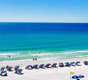 People on beach against clear blue sky