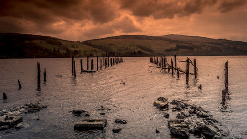 Wooden posts on beach against sky