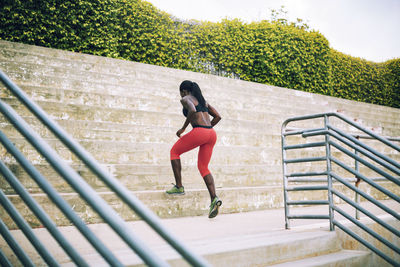 Rear view of sportswoman running on steps in stadium