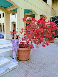 Woman standing by flower plants against building