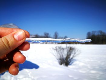 Close-up of hand holding snow against clear sky