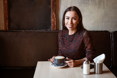 Young woman at a table in a cafe with coffee person