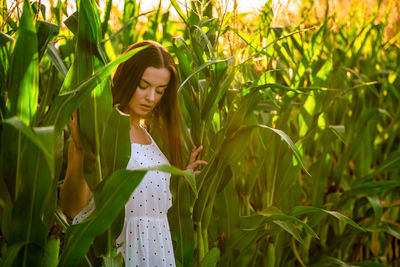 Portrait of young woman standing amidst plants