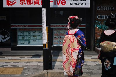 Rear view of woman with text on street in city