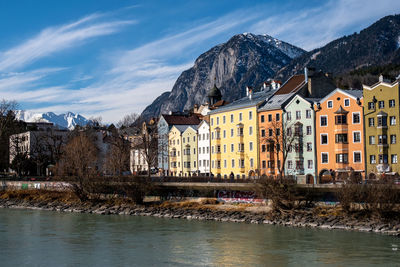 Buildings at waterfront against cloudy sky